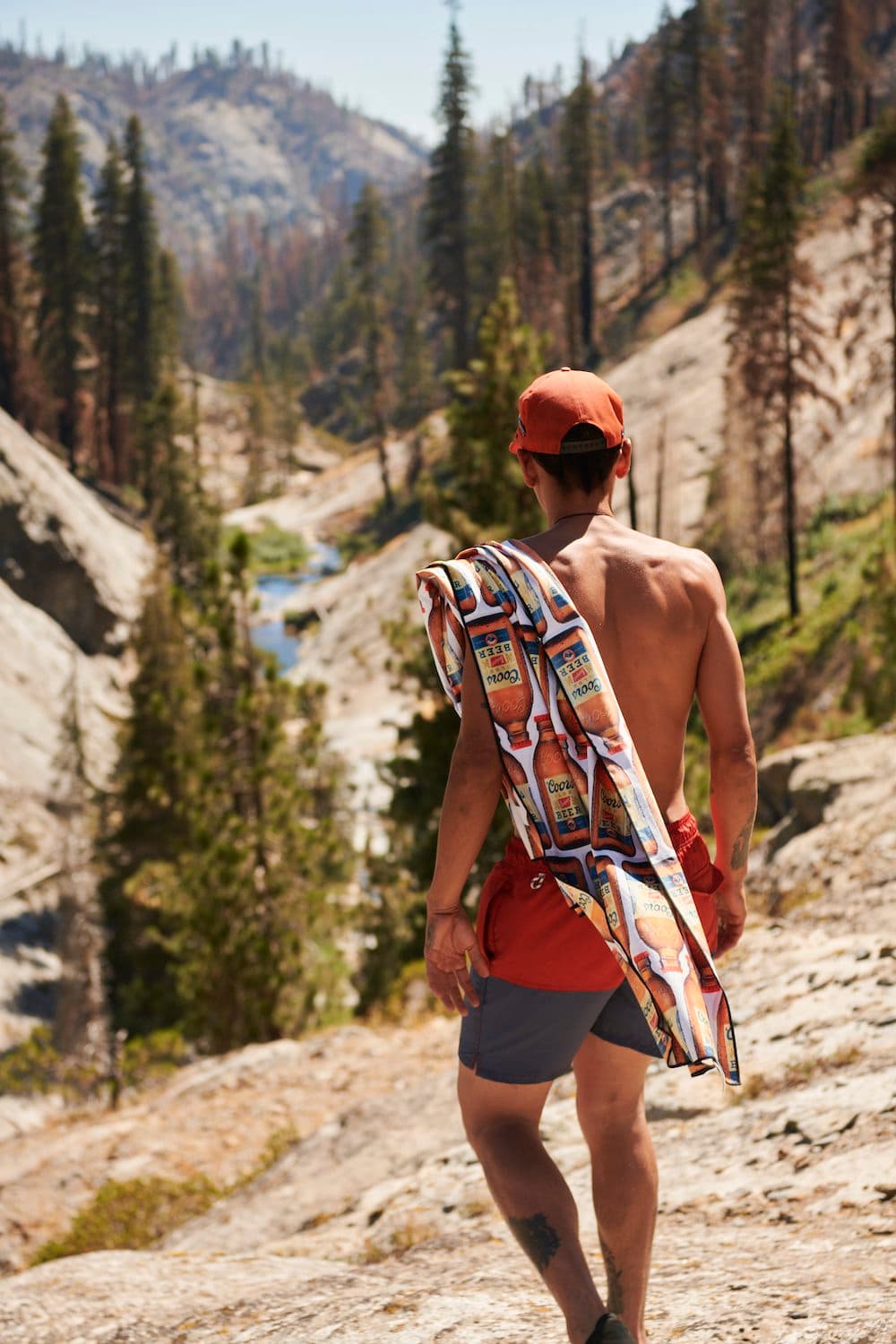person walking on rocky hills with towel on shoulder