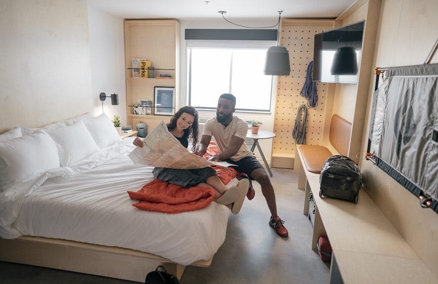 couple looking at a map of hiking trails sitting on a large bed inside a camper