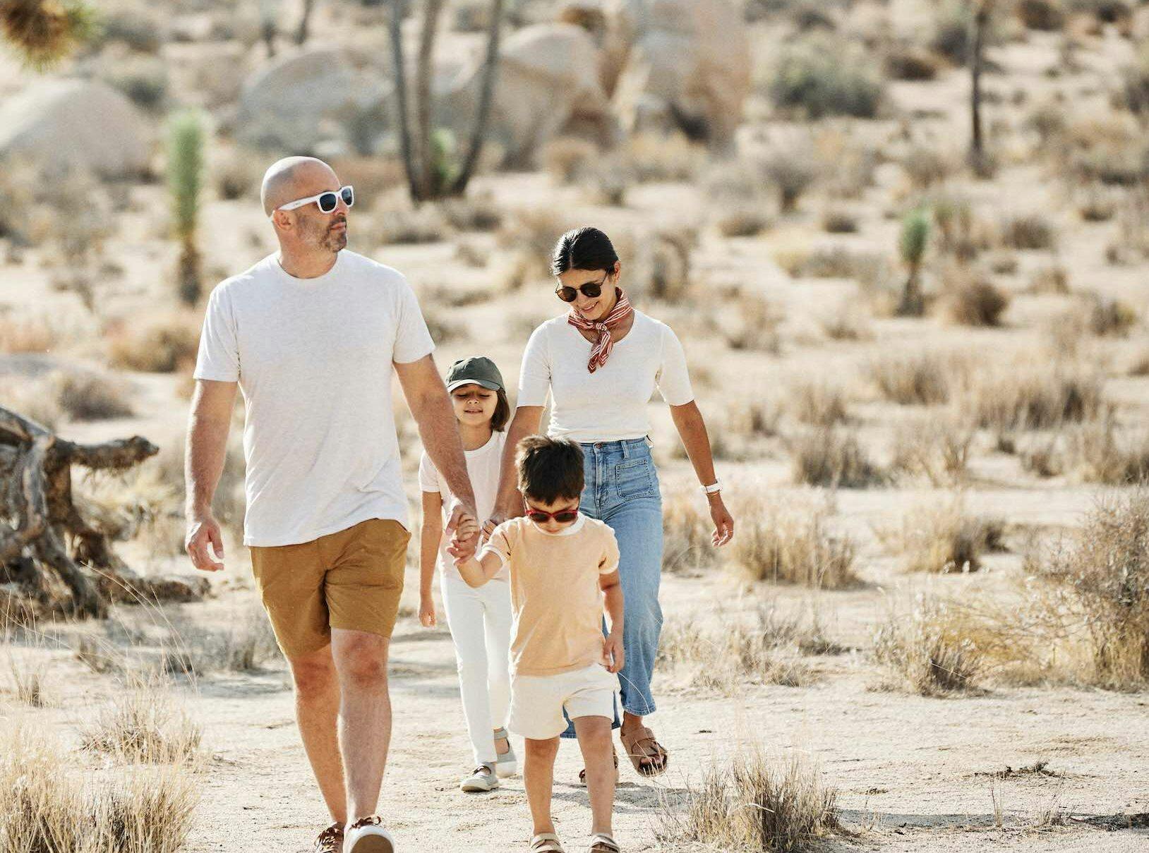 A family with 2 young children walking in a desert