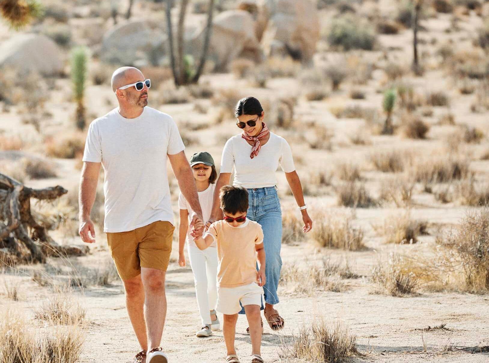 A family with 2 young children walking in a desert